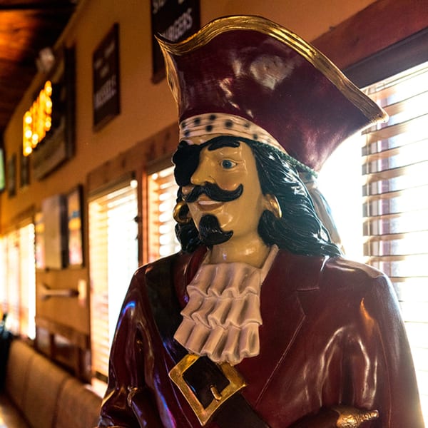 A pirate statue with an eyepatch and ruffled shirt in the Bum Rogers Crab House.