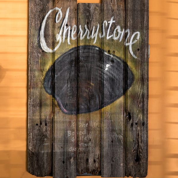 Rustic wooden sign for Bum Rogers Crab House, advertising "Cherrystone" clams with cooking options.